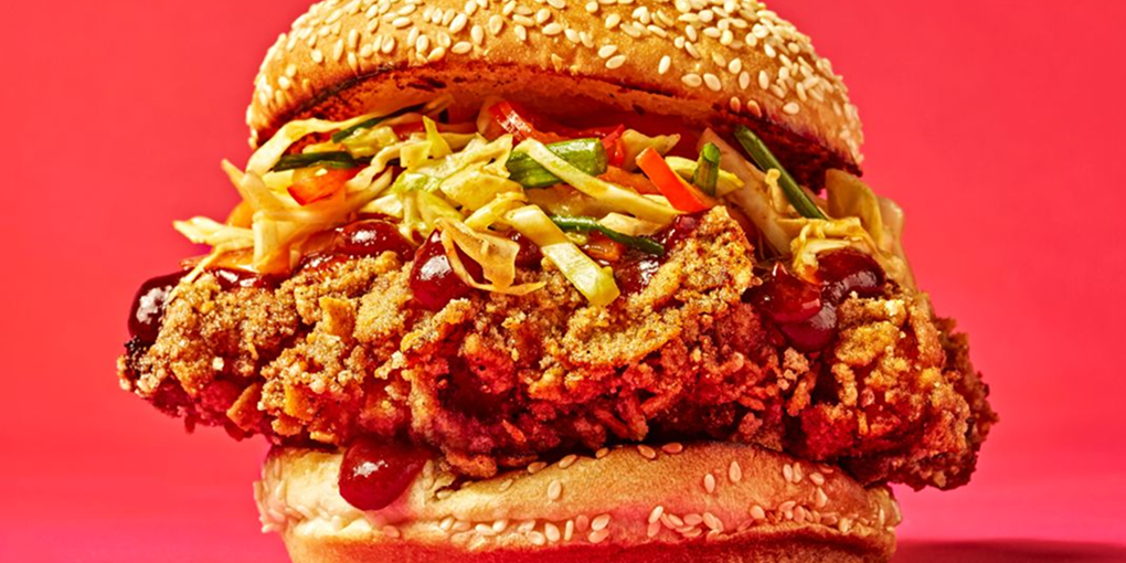 A Hencraft Fried Chicken Sandwich with slaw and sauce on a sesame seed bun.