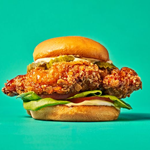 A Hencraft Fried Chicken Sandwich with lettuce, pickles, and sauce on a bun.