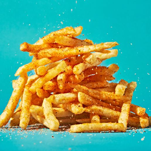 A stack of Hencraft Hen Fries with seasoning sprinkled on top.